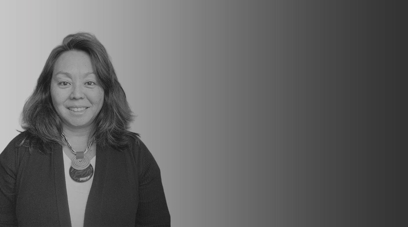 Mulher de traços orientais e cabelo castanho com mechas loiras na altura dos ombros, sorri para foto. Ele veste casaco preto, blusa branca e colar nas cores azul, branco e dourado com dois pingentes redondos. É a dra. Larissa Mitie Hojo.