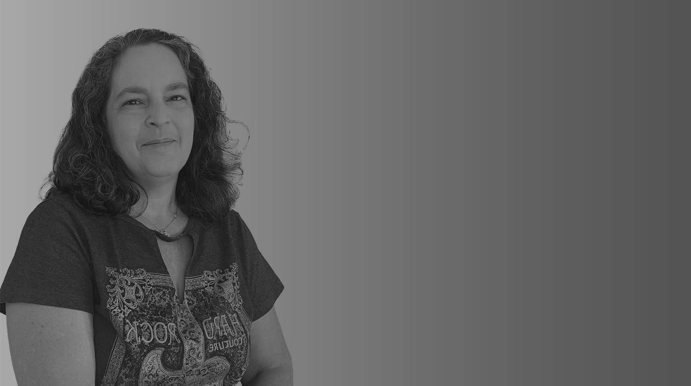 Imagem ilustrativa traz uma mulher branca, com cabelos grisalhos na altura dos ombros, vestindo camiseta com estampa. Esta é a Dra. Aline de Zoppa.