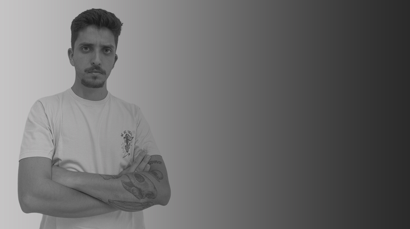Homem jovem branco pousando para foto. Ele veste blusa verde clara e braços cruzados sobre o peito.Ele tem uma tatuagem em um dos braços. Esse é Andre Vicente Montera.