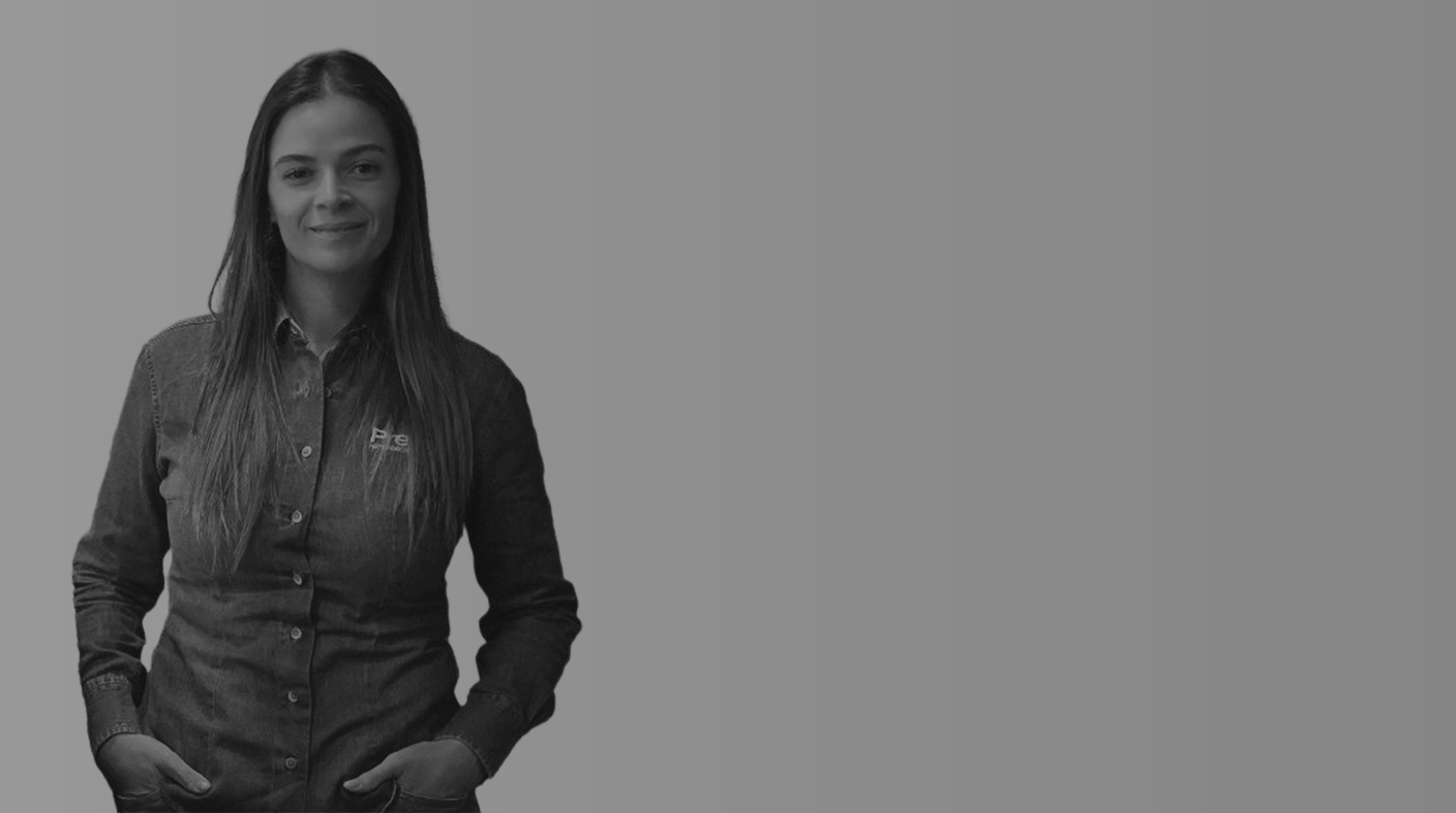 Mulher branca de fios lisos e longos em pé pousando para foto. Ela veste calça e blusa de manga longa, ambos jeans e está com as mãos nos bolsos da calça. É Gabriela do Vale Pombo.