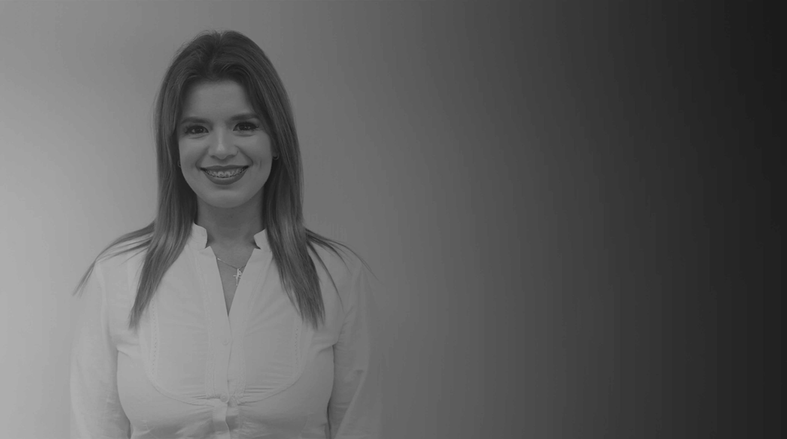 Mulher branca de fios lisos médios e loiros sorri para foto. Ela veste blusa branca de manga longa e botões. Essa é Juliana Kopczynski Fernandes de Lima Pedroso.