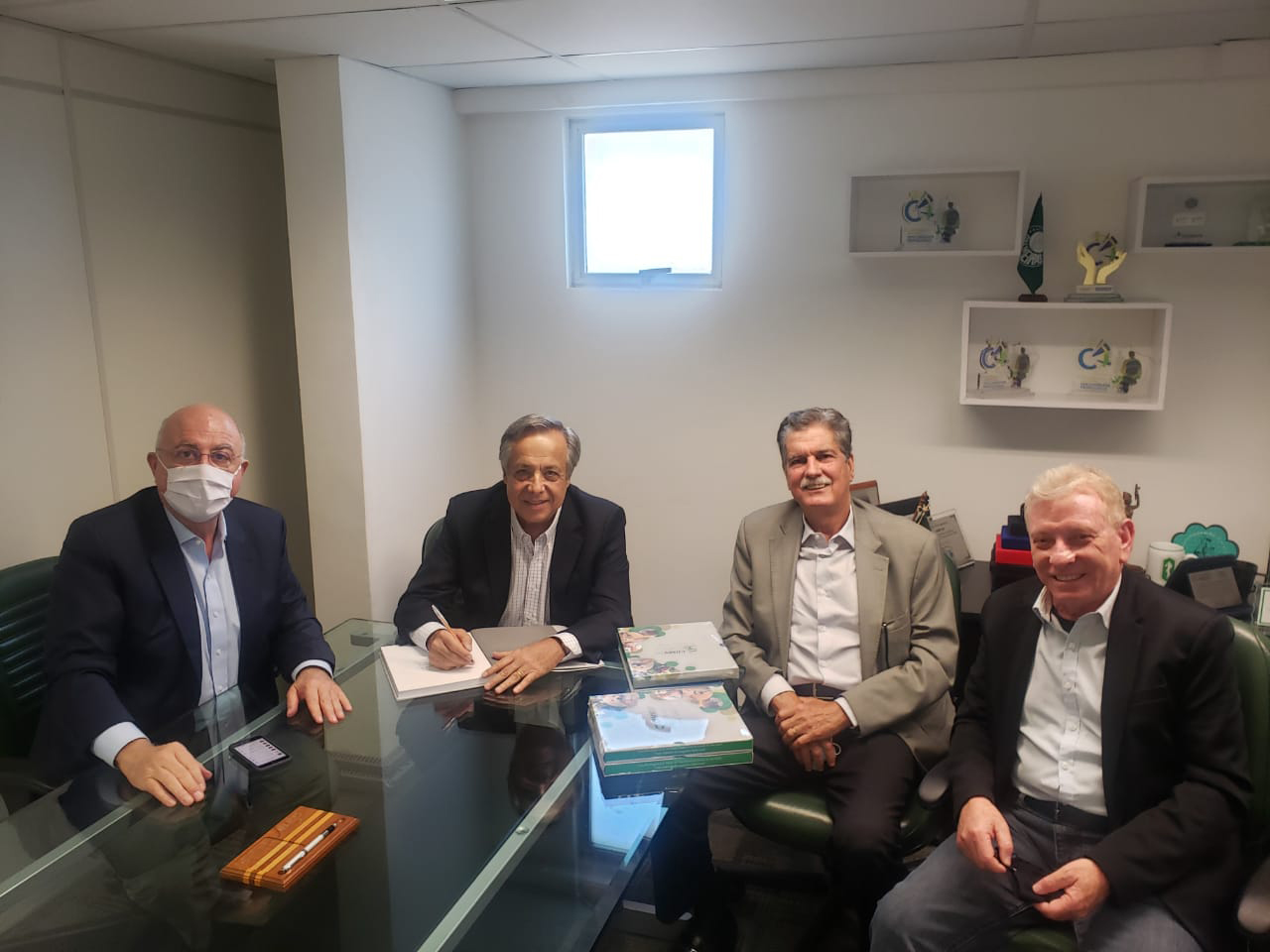 Sentados ao redor de uma mesa de vidro e sorrindo estão o deputado federal Arnaldo Jardim (a esquerda), o presidente do CRMV-SP, Mário Eduardo Pulga, o ex-presidente do Conselho, Francisco Sérgio Ferreira Jardim, e o vice-presidente do Regional, Odemilson Donizete Mossero