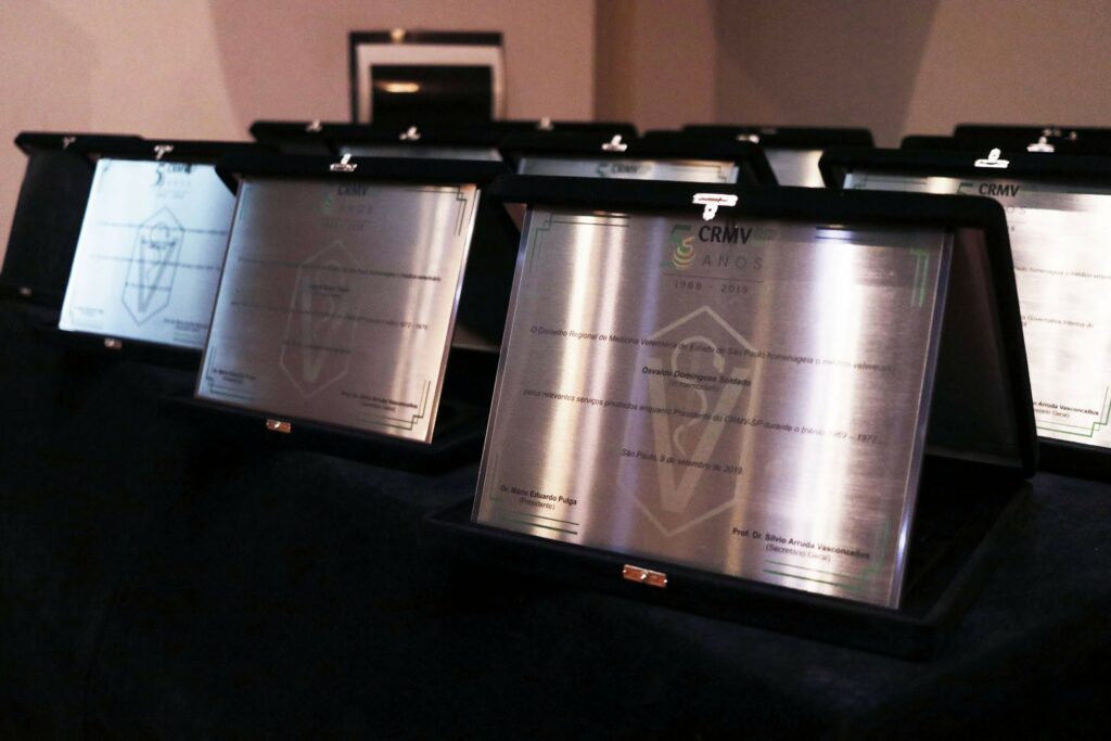 Placas metalizadas dos prêmios do CRMV-SP em estojo preto dispostas sobre uma mesa