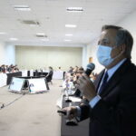 Presidente do CRMV-SP, Mário Eduardo Pulga, está de pé, com máscara, e falando ao microfone em frente dos demais convidados