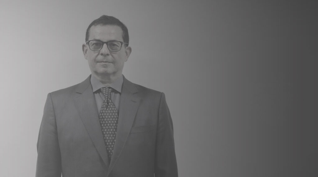 Um homem de óculos, trajando terno e gravata. Esse é o Dr. Fernando Gomes Buchala.