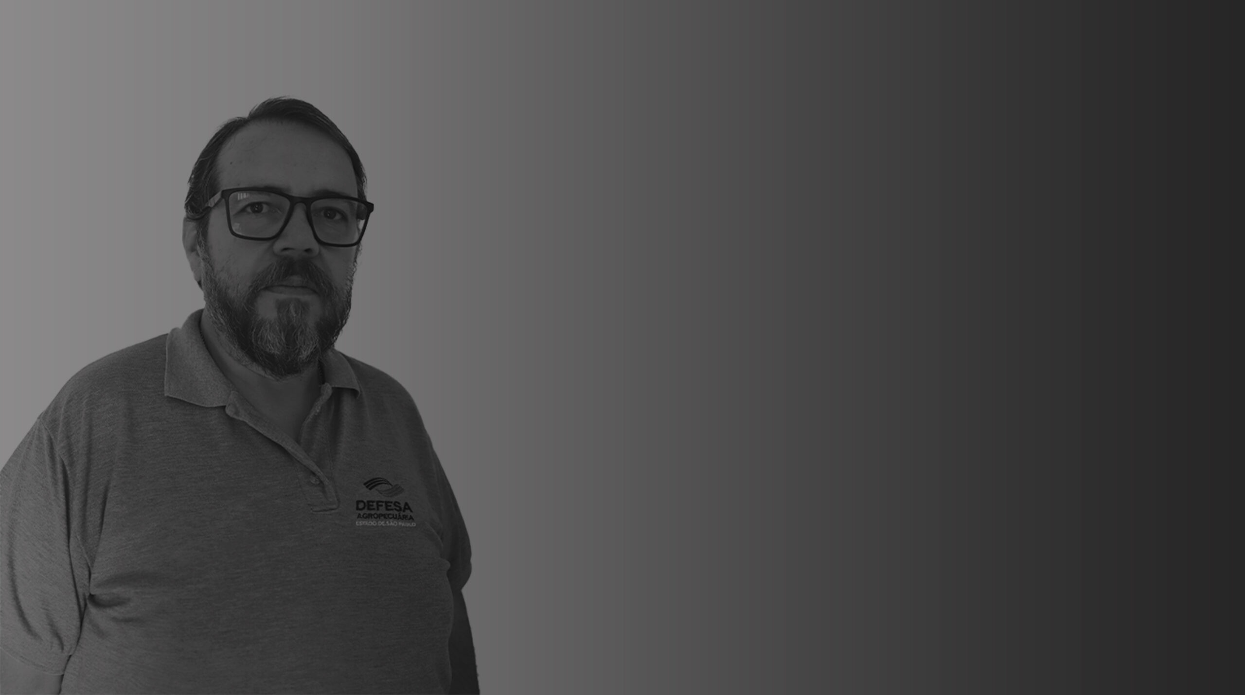 Homem branco com barba, cabelos curtos e alinhados, e óculos de armação preta quadrada. Veste uma camisa polo com a logomarca da Defesa Agropecuária. Este é Affonso dos Santos Marcos.