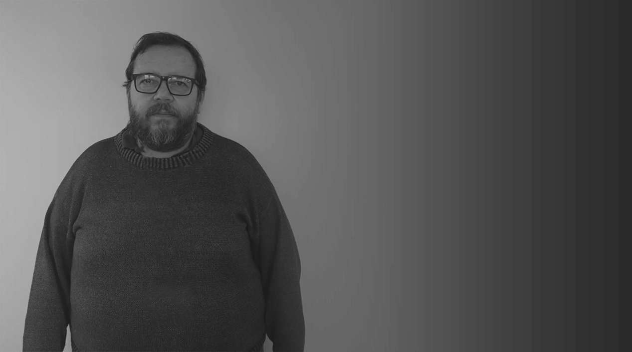 Homem branco adulto em pé de fios pretos e barba com cavanhaque. Ele usa óculos quadrado de armação preta grossa e veste casaco de lã preto. É o dr. Affonso dos Santos Marcos.