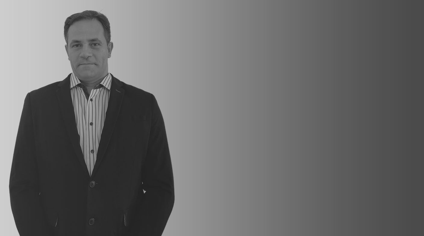 Homem alto de fios pretos e curtos, de pé pousando para foto. Ele veste camisa social listrada de botões brancos redondos e blazer azul marinho. É o dr. Arthur Luiz de Almeida Felício.