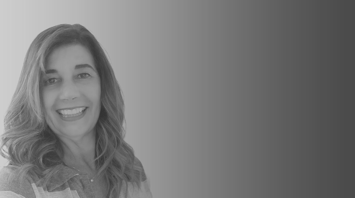 Mulher de fios loiros escuros e lisos, sorrindo para foto, ela veste blusa cinza listrada. É a dra. Monica Tavares Junqueira.