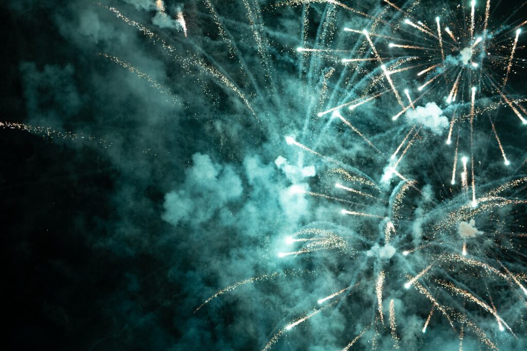 Imagem traz uma queima de fogos de artifício branco com fumaça em um céu escuro.