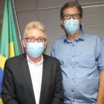 Presidente do Conselho e RT do Zoológico posam para a foto em frente a bandeira do Brasil. Ambos estão de máscara.