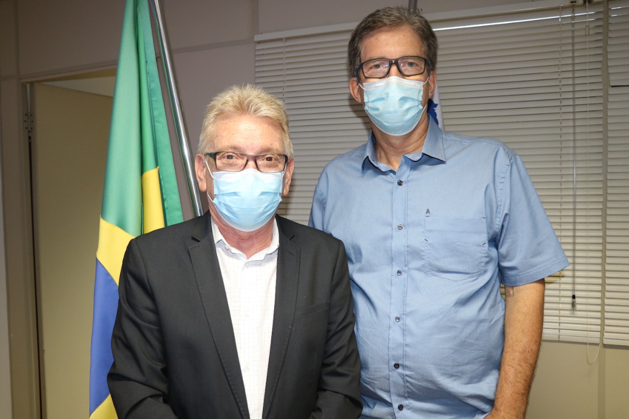 Presidente do Conselho e RT do Zoológico posam para a foto em frente a bandeira do Brasil. Ambos estão de máscara.