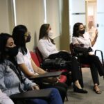 Cinco colaboradores das Unidades Regionais sentados, usando máscaras e ao fundo uma parede branca.