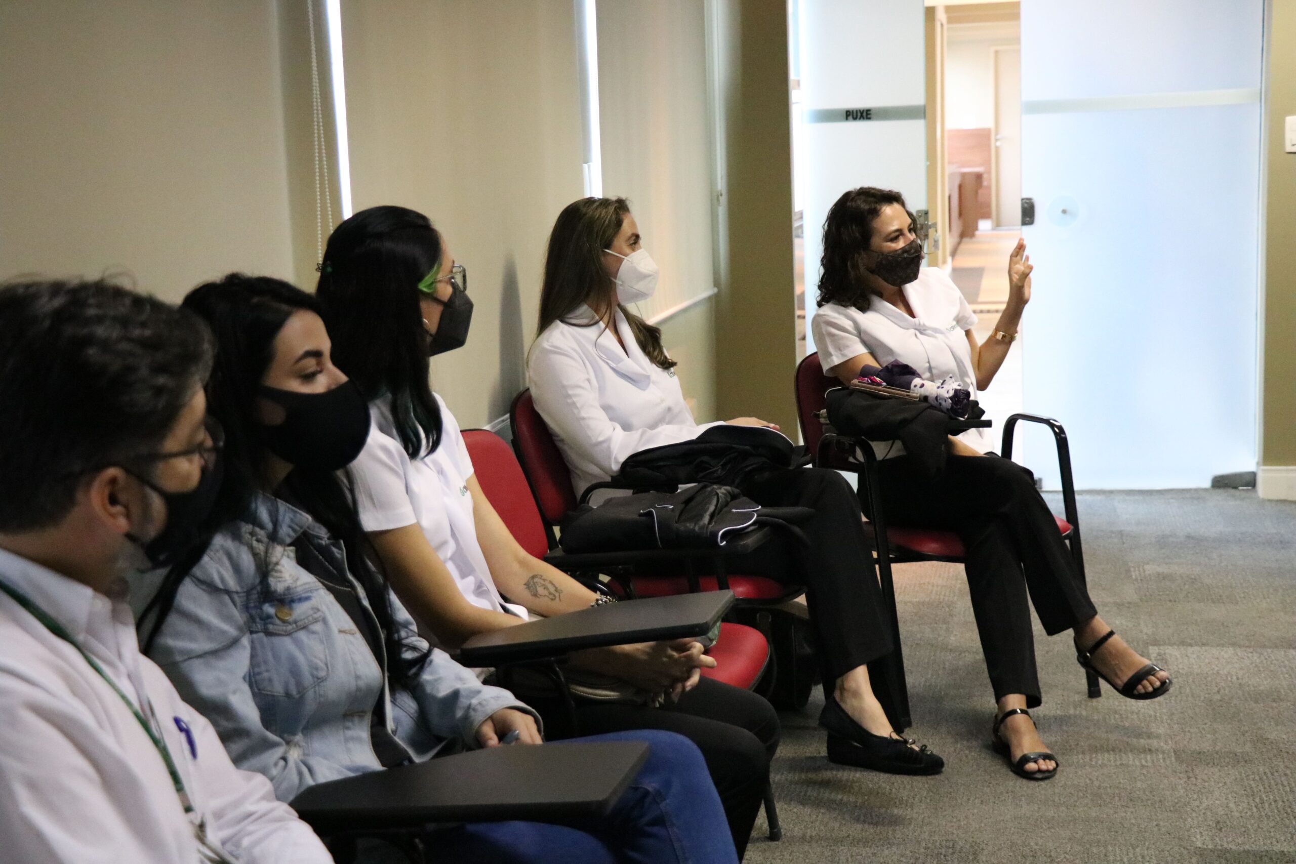 Cinco colaboradores das Unidades Regionais sentados, usando máscaras e ao fundo uma parede branca.