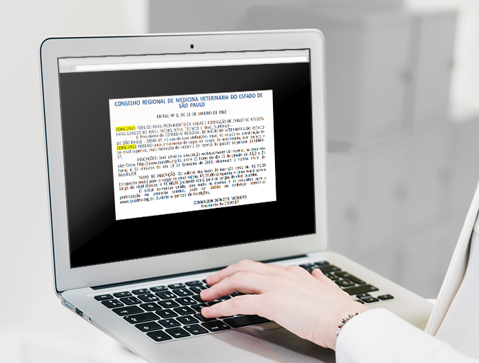 Na imagem aparece um notebook e uma mão apoiada no teclado do mesmo. Na tela aparece o extrato da publicação do edital do concurso do CRMV-SP.