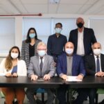 Na foto aparecem quatro pessoas sentadas e três atrás destas de pé. São duas mulheres e cinco homens. Todos estão de máscara e posam para a foto.