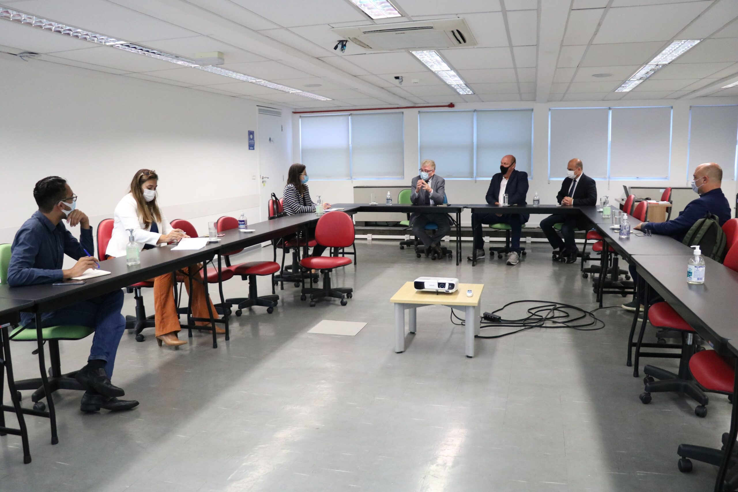 Na foto aparecem mesas dispostas em formato de "U" em cujo entorno estão sentadas sete pessoas, com distanciamento entre si e vestindo máscaras. Liderando a reunião, o presidente e o vice-presidente do CRMV-SP.