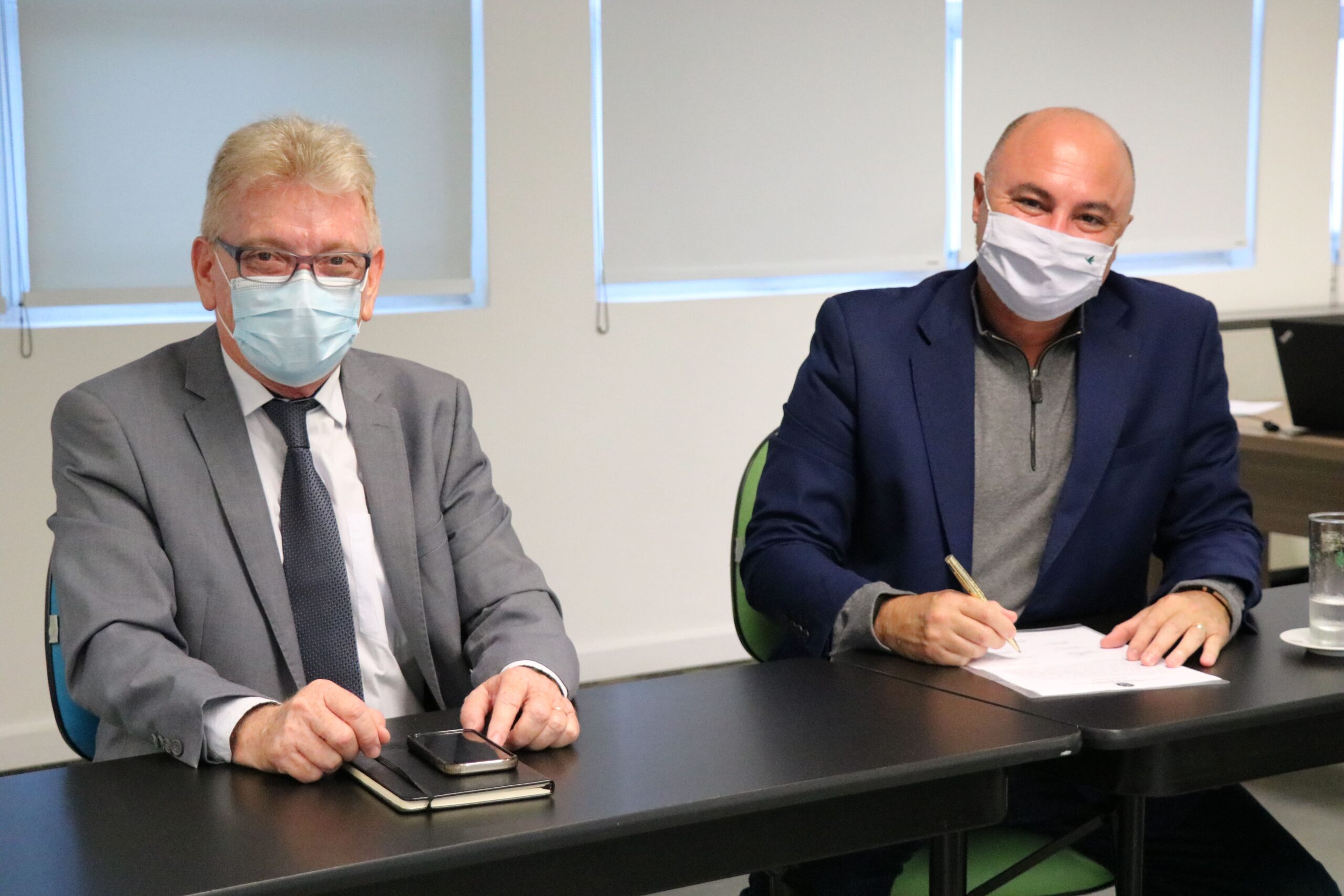 Na foto estão sentados lado a lado e de máscara, posando para a câmera, o presidente do CRMV-SP e o presidente da Comissão de Nutrição Animal, que faz a menção de assinar o termo de posse.