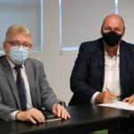 Na foto estão sentados lado a lado e de máscara, posando para a câmera, o presidente do CRMV-SP e o o médico-veterinário Rodolfo Claudio Spers, que faz a menção de assinar o termo de posse como integrante da Comissão de Nutrição Animal.