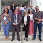 Representantes de regionais do Sul e Sudeste posam para foto em frente a sede do CRMV-MG. O coordenador financeiro do CRMV-SP, Emanoel Coelho, aparece na foto sorrindo vestindo um suéter vinho.