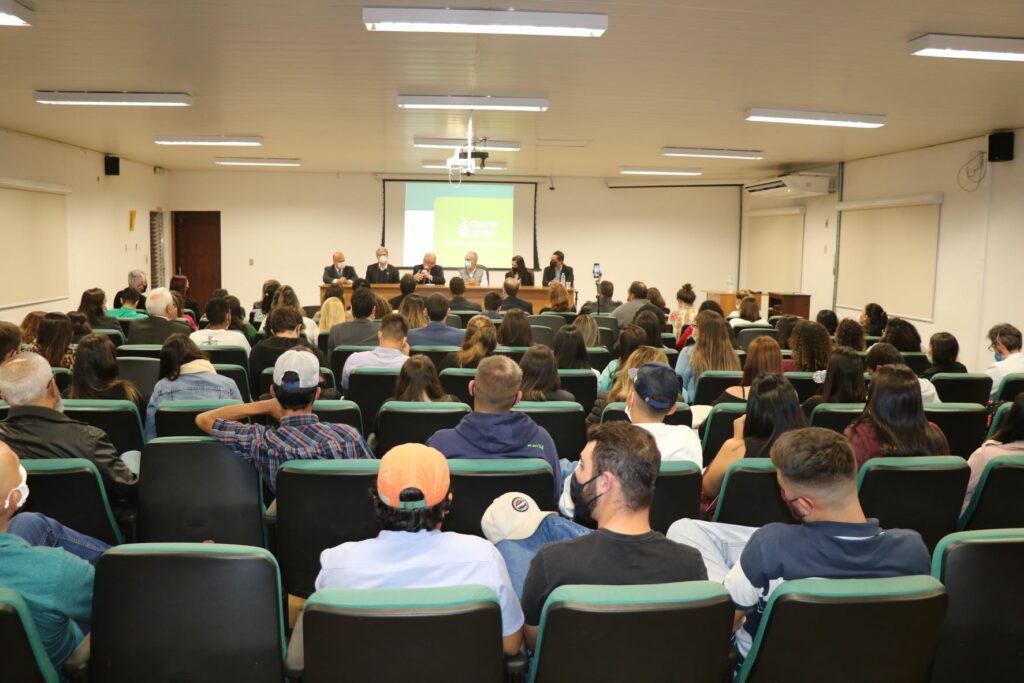 Auditório lotado da Unesp Botucatu tem ao fundo mesa composta por representantes do CRMV-SP e da faculdade de Medicina Veterinária e Zootecnia.