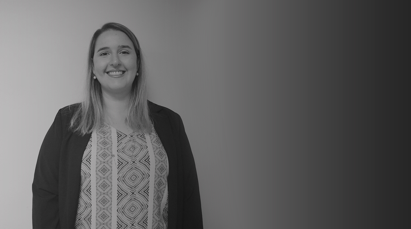 Mulher de cabelo loiro, utilizando um casaco preto com uma blusa de detalhes. Essa é o membro Daniela Denadai