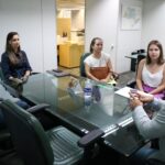 Profissionais estão reunidos ao entorno de uma mesa de vidro. Estão todos sentados e atentos ao que o vice-presidente do CRMV-SP fala.