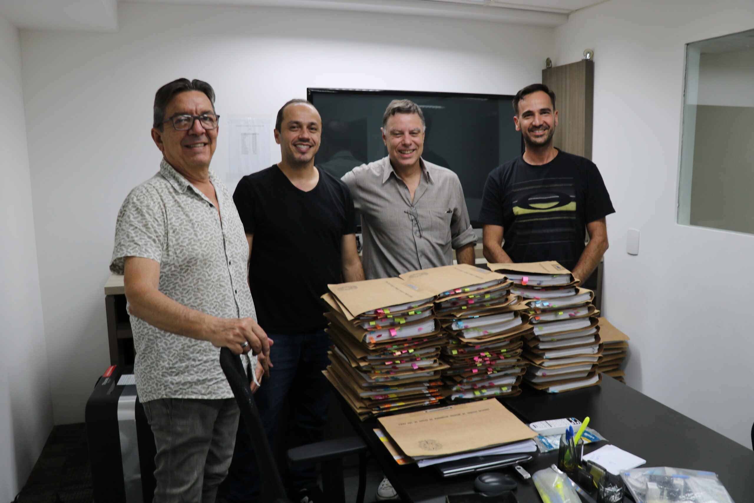 Membros da Comissão de Tomada de Contas do CRMV_SP posam para foto com as pilhas de processos em papel