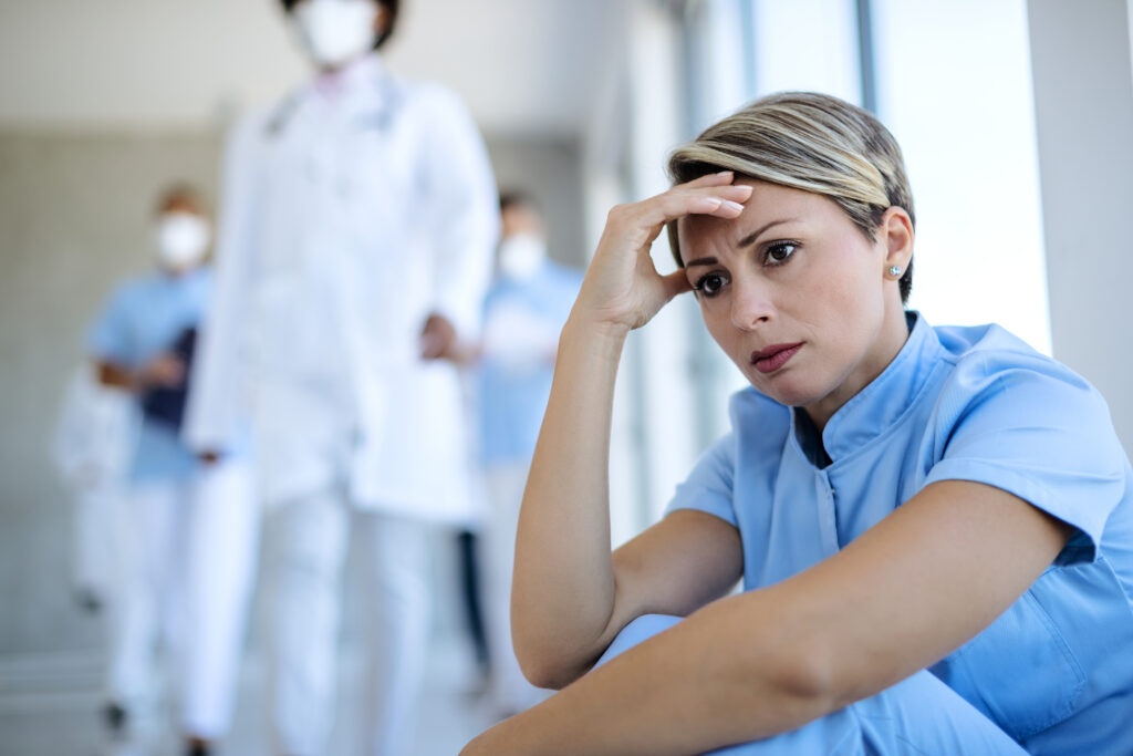 Enfermeira perturbada sentada em um corredor pensando em algo