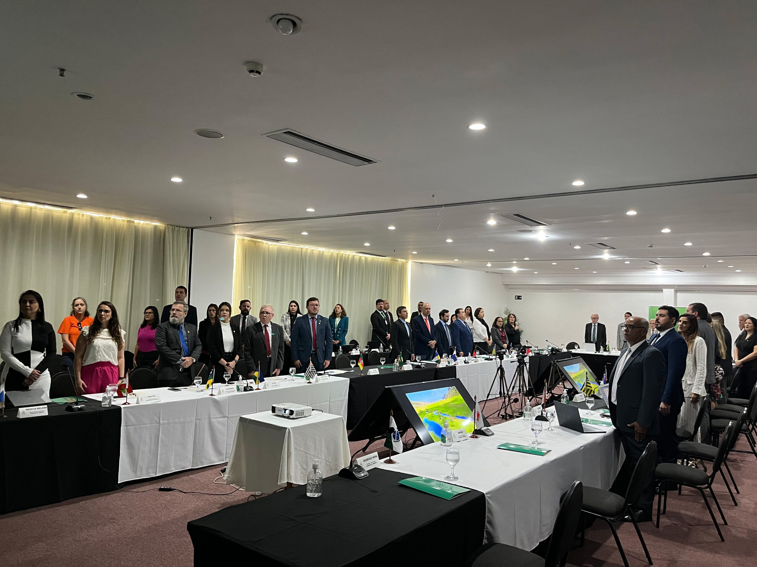 Imagem mostra pessoas dispostas em formato quadrado, com mesas na frente de cada um delas.