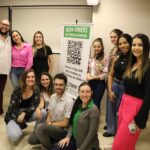 Na foto aparecem o coordenador de curso da Unimep e alunos da graduação. Eles estão posando e sorriem para a câmera. Estão posicionados parte de pé e parte agachados. Ao centro está o banner do CRMV-SP com a frase "Bem-vindos ao nosso evento".