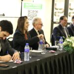 A foto mostra mesa com toalha preta e arranjo de flores composta pelo assessor jurídico, pela tesoureira, pelo presidente, pelo secretário-geral e pelo diretor técnico do CRMV-SP. Eles sorriem de maneira descontraída. O assessor jurídico faz anotações.