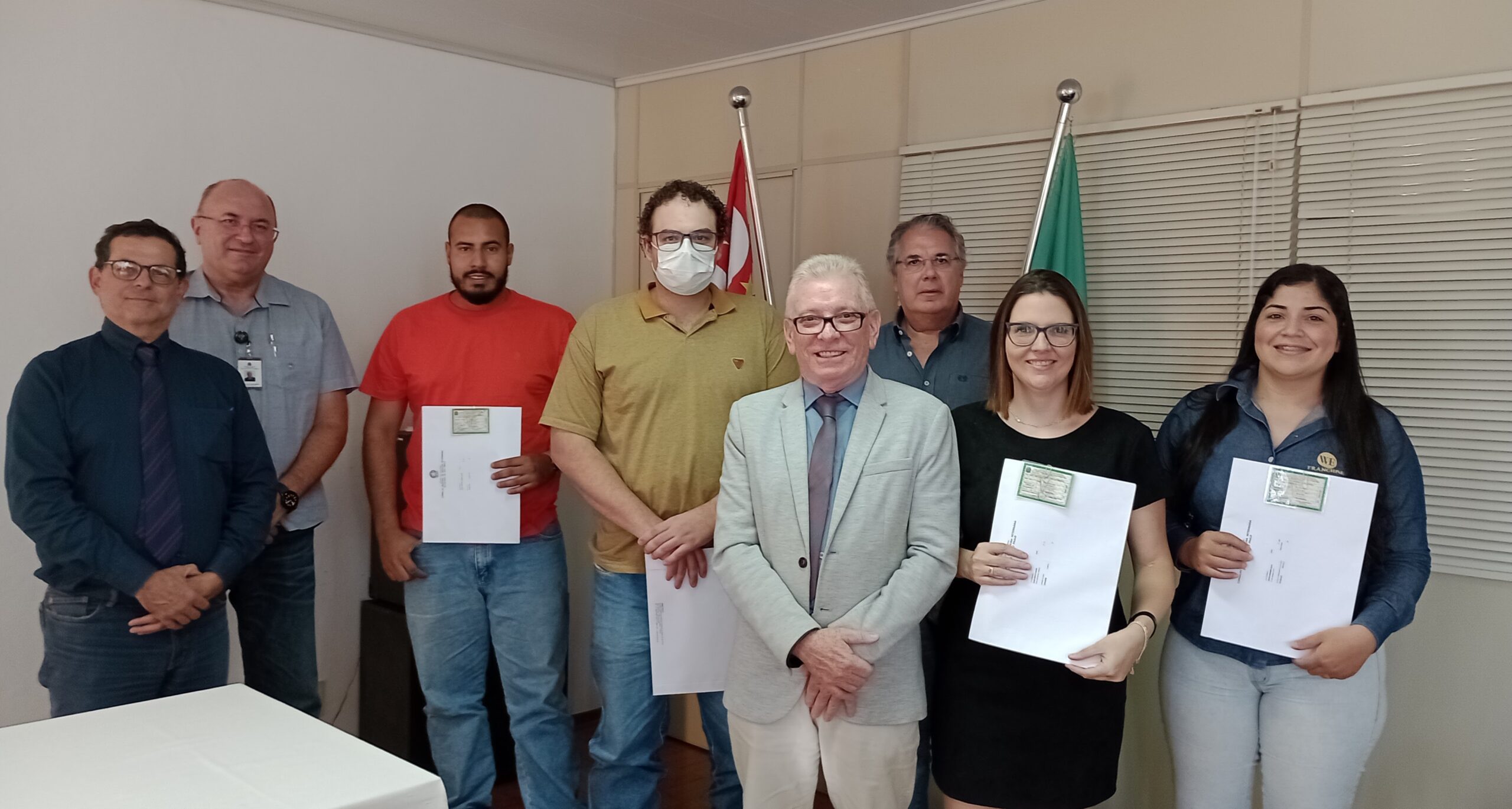 Novos profissionais que receberam a cédula de identidade posam juntos em pé mostrando os novos documentos, juntamente com o Presidente do CRMV-SP, Odemilson Mossero e com o Secretário-geral, Fernando Buchala.