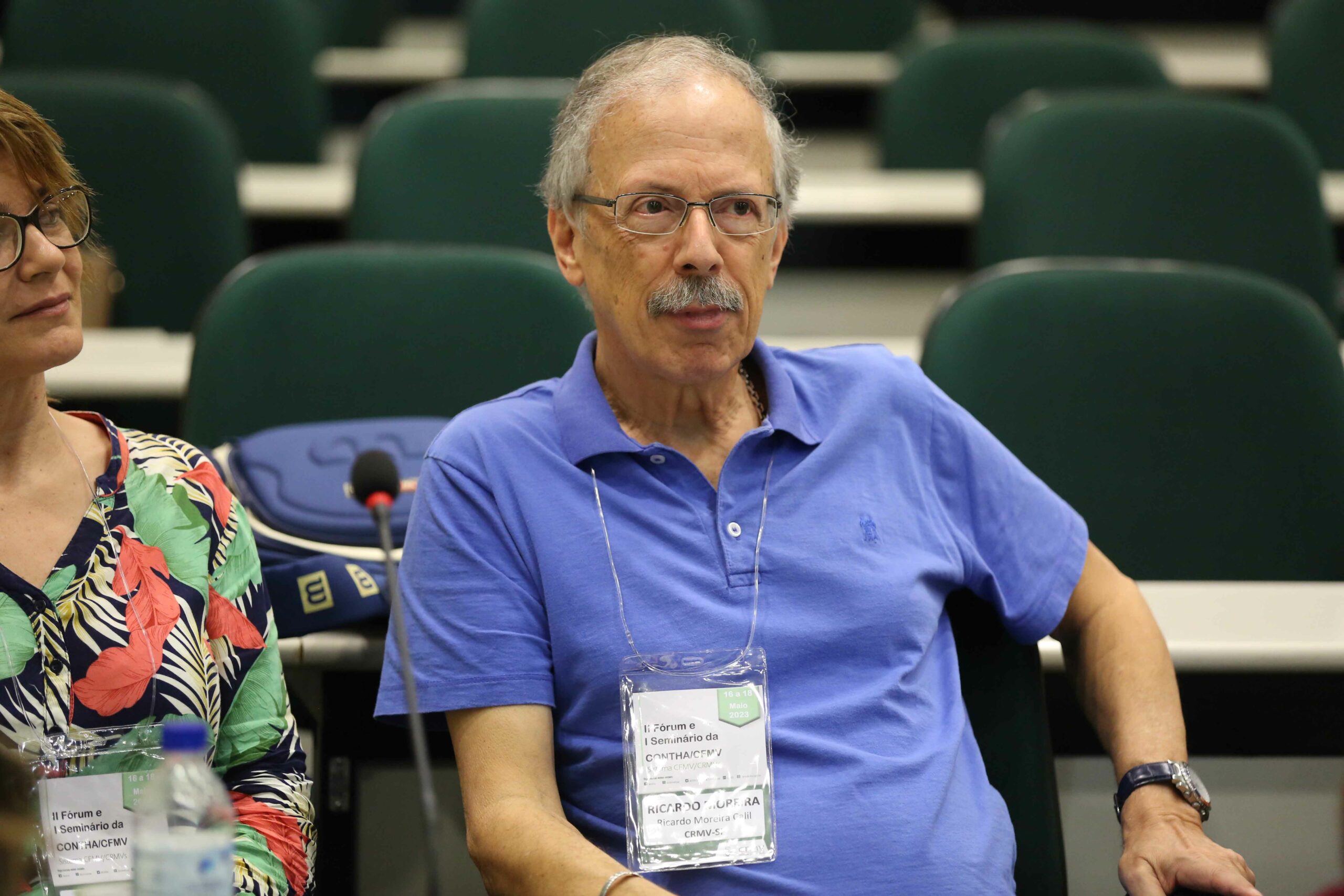 A foto mostra Ricardo Moreira Calil, médico-veterinário e presidente da Comissão Técnica de Alimentos do Conselho Regional de Medicina Veterinária do Estado de São Paulo (CRMV-SP). Ele está sentado, veste camisa azul e está prestando atenção ao evento.
