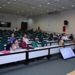 A foto mostra membros que participaram do Seminário sentados, prestando atenção no evento.