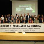 A foto mostra os participantes do Seminário no dia 15/05. Eles estão no palco, alguns estão em pé e outros estão sentados. Em frente deles, há um cartaz escrito "II Fórum e I Seminário da Contha".