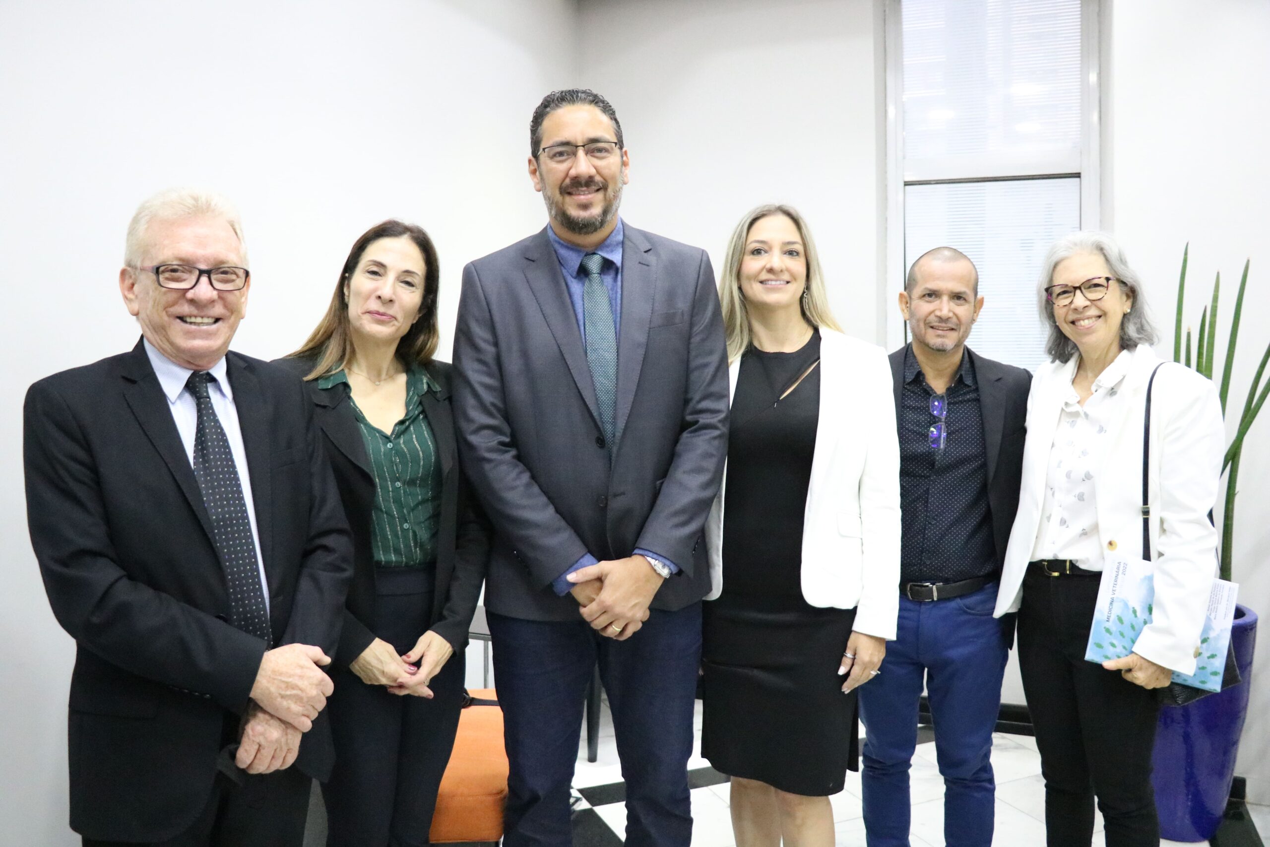 Na foto estão três homens e três mulheres. Eles estão posicionados lado a lado e sorriem para a foto.