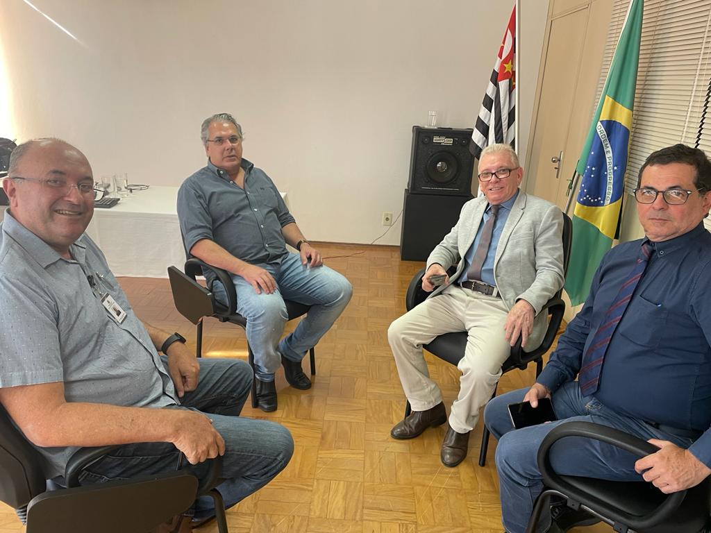 Na imagem estão quadro homens sentados. Eles estão olhando e sorrindo para a câmera. São o diretor regional da CDA, o representante regional, o presidente e o secretário-geral do CRMV-SP. Ao fundo as bandeiras de São Paulo e do Brasil.