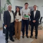 Na imagem estão quatro pessoas, sendo uma mulheres e três homens. Estão todos de pé, olhando e sorrindo para a foto. São eles: o assessor de Gabinete do CRMV-SP, a coordenadora de relacionamento com entidades, o secretário de Relações Institucionais da Prefeitura de São Paulo, e o presidente da Comissão Técnica de Políticas Públicas. O secretário está mais ao centro e segura um relatório de gestão do CRMV-SP.