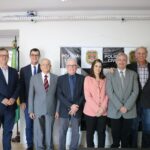 Na foto os representantes do CRMV-SP, da associação de médicos-veterinários de Piracicaba e o delegado seccional da cidade estão de pé, em frente a um painel da polícia civil, posicionados lado a lado, e sorriem para a câmera.