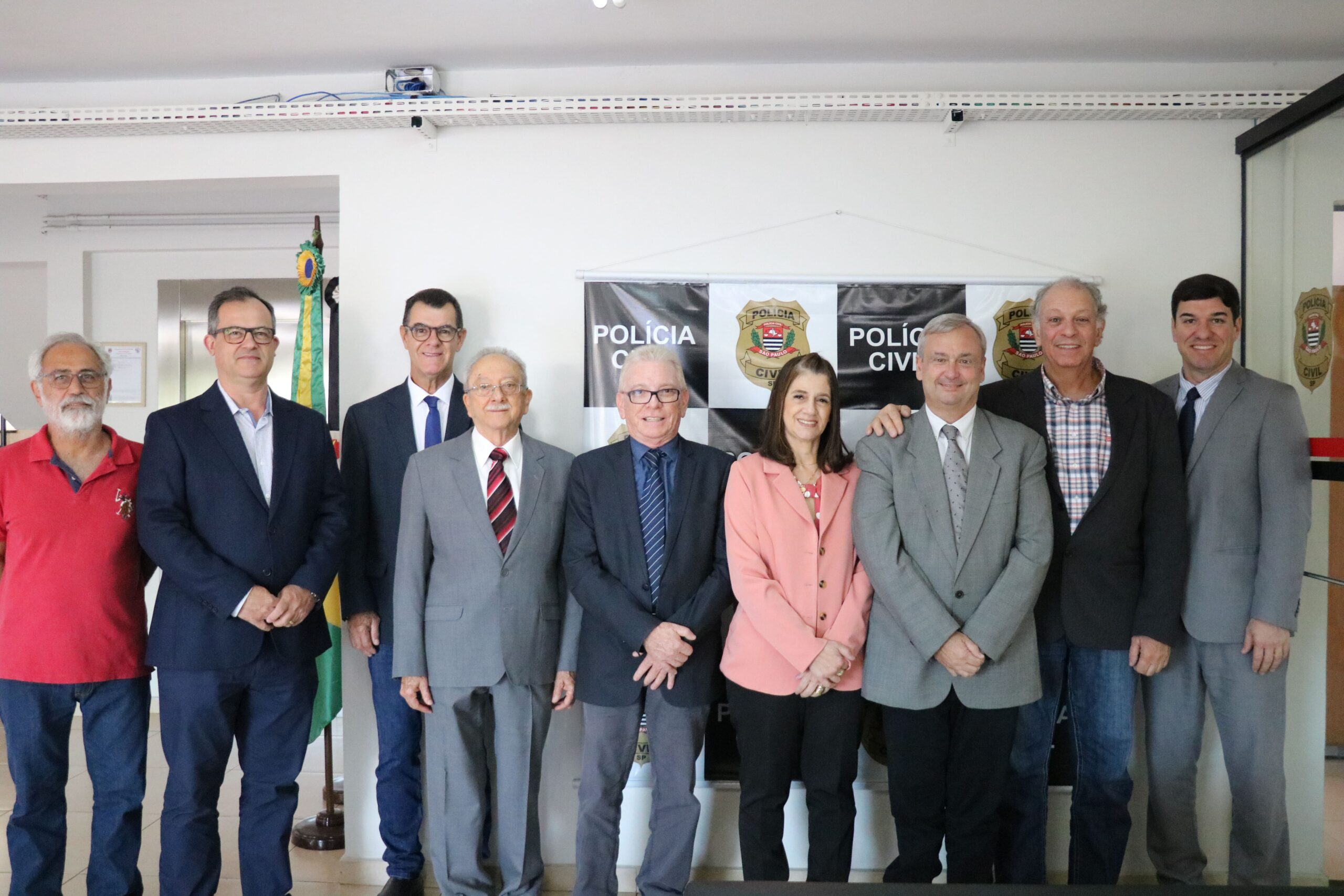 Na foto os representantes do CRMV-SP, da associação de médicos-veterinários de Piracicaba e o delegado seccional da cidade estão de pé, em frente a um painel da polícia civil, posicionados lado a lado, e sorriem para a câmera.