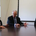 Na foto aparecem o integrante da Comissão de Saúde Ambiental, a esquerda, o delegado de polícia diretor do Deinter 9, ao centro, e o presidente do CRMV-SP, a direita. Eles vestem terno e estão sentados ao entorno de uma mesa de madeira conversando.