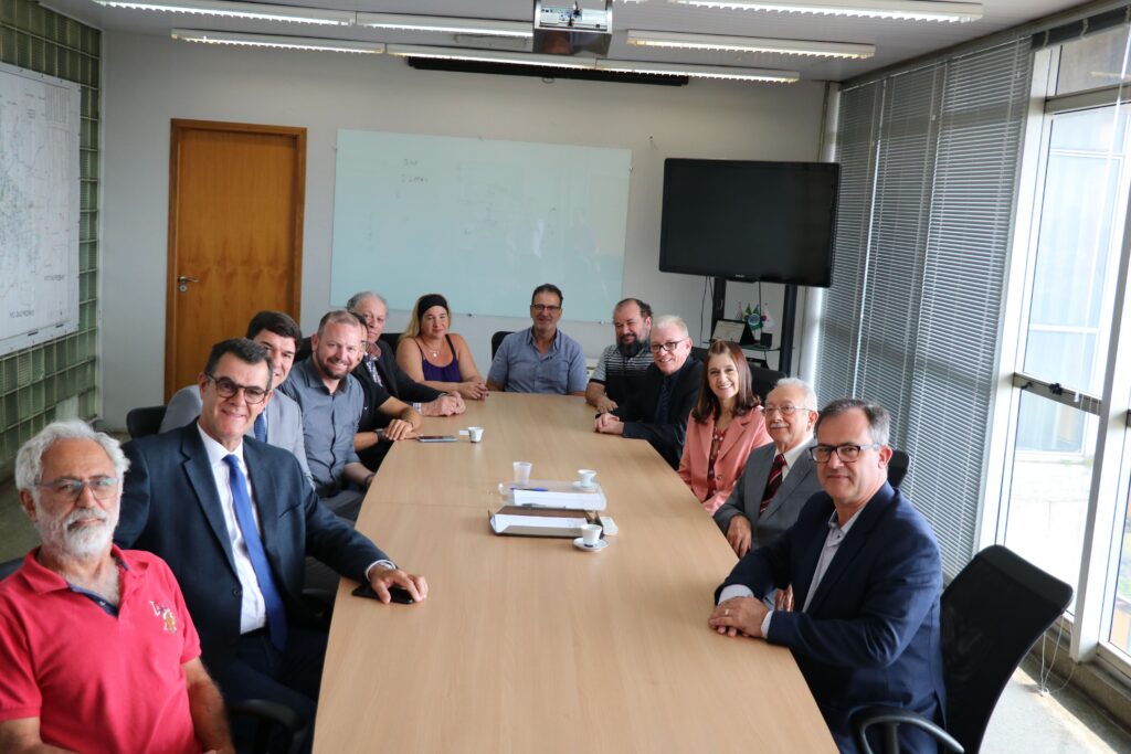 Na foto estão os representantes do CRMV-SP e da associação de médicos-veterinários de Piracicaba com uma vereadora da cidade, o diretor do DBEA, o secretário de Saúde e o prefeito de Piracicaba. Estão todos sentados no entorno de uma mesa retangular de madeira. O prefeito está na cabeceira. Todos estão olhado para a câmera. Há 11 homens e duas mulheres.