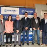 Na foto está a Comitiva do CRMV-SP, formada por seis homens e uma mulher. Também está presente o tesoureiro da Associação de Médicos-veterinários de Piracicaba. Estão todos de pé, sorrindo para a foto, em frente ao painel da Prefeitura de São Paulo.