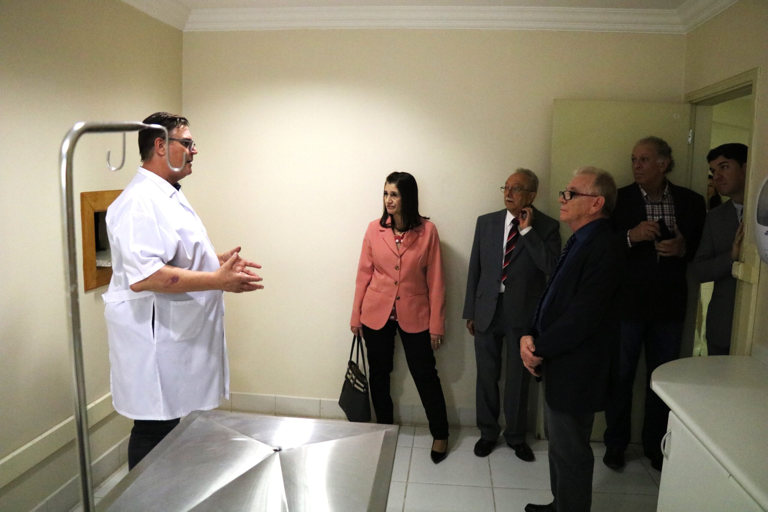 Na foto aparecem cinco representantes do CRMV-SP, acompanhados pelo responsável da clínica da Unimep. Eles estão dentro de uma sala de atendimento e na imagem aparece uma mesa de aço inos com suporte para medicações. Há cinco homens e uma mulher.