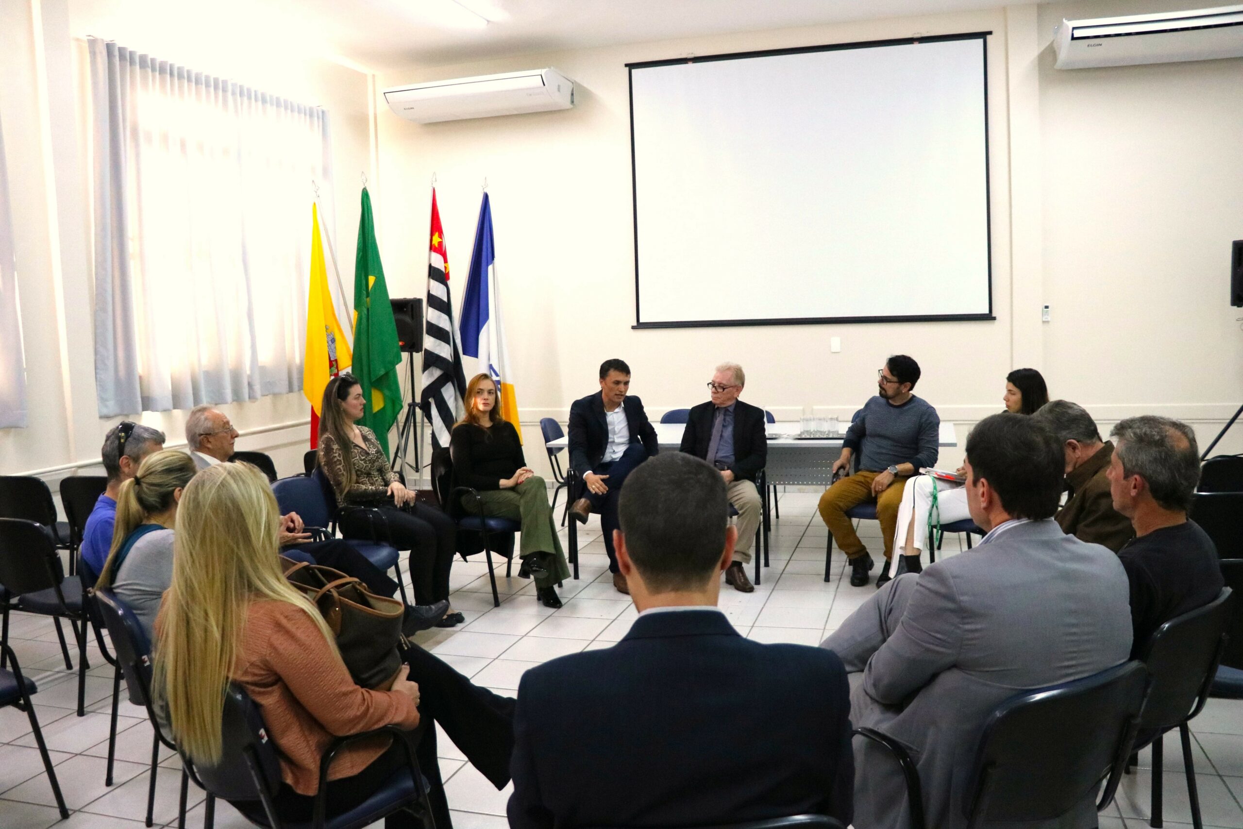 Na foto há 15 pessoas sentadas em carteiras escolares formando uma roda de conversa. Em destaque aparecem os presidentes da Ammvet e o secretário de Bem-estar Animal. No fundo da sala há bandeiras do Brasil, do estado de São Paulo, do município de Mogi Guaçu e do Cegep.