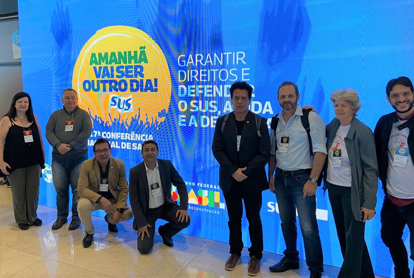 Na foto há seis pessoas em pé, sendo quatro homens e duas mulheres e dois homens agachados, todos posando para a foto.