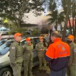 Orientação à equipe de médicos-veterinários voluntários. Eles estão em pé, encostados no carro, e à frente está uma pessoa passando informações.
