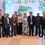 Representantes de diversas regionais do CRMV posam para a foto. Ao fundo, está o cartaz com o logo do CRMV-RN, em verde.