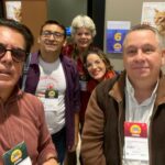 Na foto há cinco pessoas, sendo três homens e duas mulheres. Estão em pé posando para a foto.